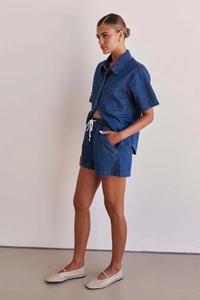 Detail view of washed blue denim texture on summer short-sleeved shirt and drawstring shorts