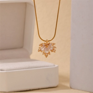 Macro shot of a golden maple leaf pendant necklace with zircons over a jewelry box