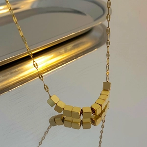 Gedetailleerde macro-opname van gouden vierkante kralenketting op zilveren dienblad