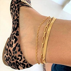 Detailed view of triple gold-layered anklets with flat snake and paperclip chain links