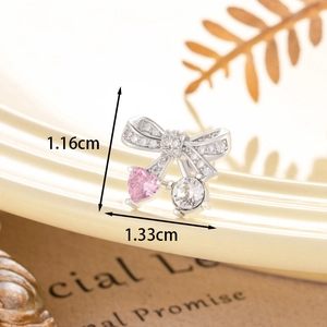Cute bow stud earring with pink heart and white zircon on a ceramic plate