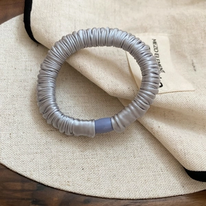 Close-up of silver-grey satin-covered spiral hair tie with purple joint detail
