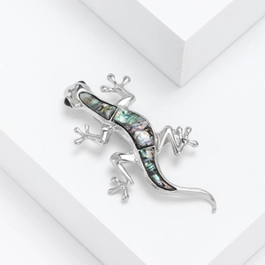 Detailed macro shot of silver gecko brooch with iridescent abalone shell inlay