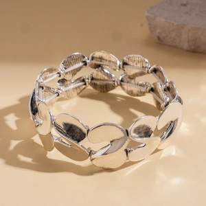 Detail of silver twisted S-shape metallic elastic bracelet with vintage blackened finish