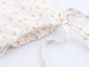 Detail der Blumenprint-Bluse mit elastischem Bündchen und Schleife auf weißer Baumwolle