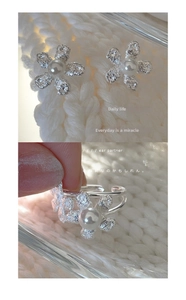 Detailed view of silver flower ring and earrings set with pearls on white knit fabric
