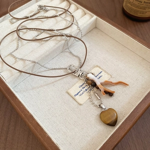 Close-up of double-layer necklace with tigers eye heart pendant and coral charm details