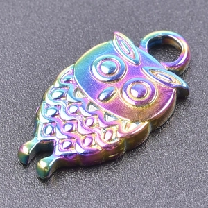 Macro shot of owl pendant with colorful iridescent plating on black texture background