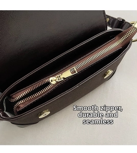 Detail of smooth golden zipper and magnetic closure on dark brown matte leather bag
