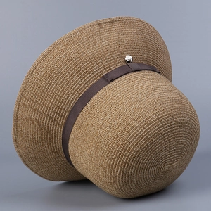 Detailed view of the woven texture and ribbon band of a summer straw fisherman hat.