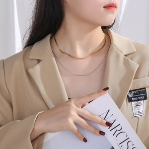 Close-up of double-layered gold and silver snake bone necklaces worn on a model