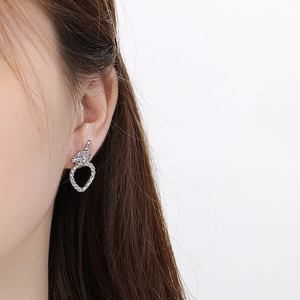 Gros plan d'un mannequin portant des boucles d'oreilles cœur tissées en acier argenté