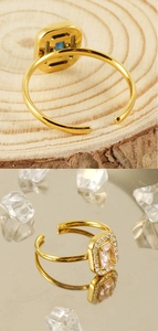 Detail of gold square adjustable ring with pink gemstone and halo on mirror background