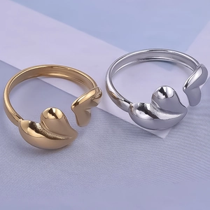 Detailed view of adjustable gold and silver heart-shaped rings on a textured background