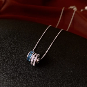 Detail of silver necklace with circular pendant featuring blue and white cubic zirconia stones