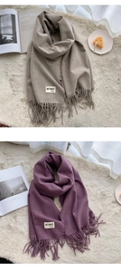 Detail shot of solid color cashmere-feel scarf fringe and premium brand label