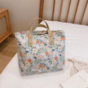 Detail of floral canvas tote with retro daisy print and vintage brown leather handles