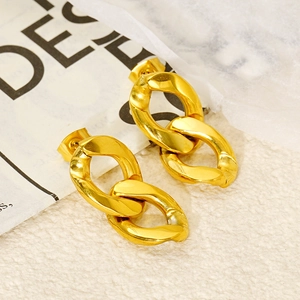 Detailed view of gold-plated interlocking figure-eight earrings on a textured white surface