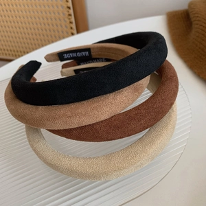Detail of four padded suede headbands in brown tones on a glass tray with handmade labels