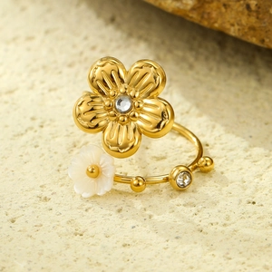 Detail of 18K gold flower ring featuring white shell inlay and zircon crystal accents