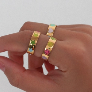 Close-up of gold rings with colorful enamel stars, smiley faces, and hearts on fingers