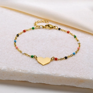 Golden heart charm bracelet with colorful enamel beads on a marble and silk backdrop
