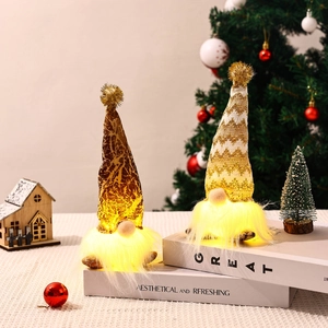 Detail of two lighted Christmas gnomes with knitted gold hats on decorative books