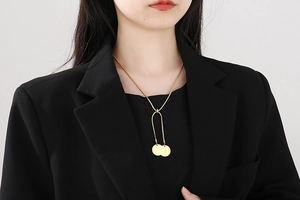 Close-up of golden snake chain necklace with dual round pendants on a black suit