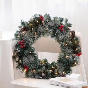 Noorse 45cm kerstkrans met LED-verlichting, dennenappels en rode bessen op een stoel