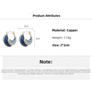 Detail view of twisted C-shaped blue enamel earrings with gold trim and 2x2cm dimensions