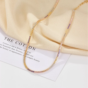 Detail of gold necklace with colorful round zircons on silk background and card