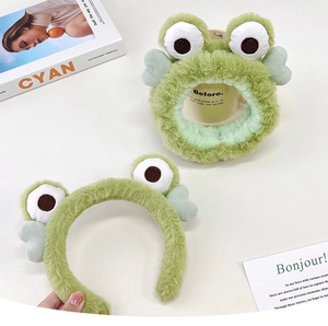 Close-up of a plush green frog headgear set with eyes and cute heart details