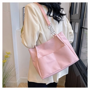 Borsa tote in PU rosa con catena indossata da una modella in un caffè luminoso