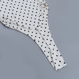 Détail montrant le motif à pois noirs et la couture fine sur le tissu blanc