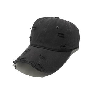 Close-up of distressed details and frayed holes on a vintage black baseball cap