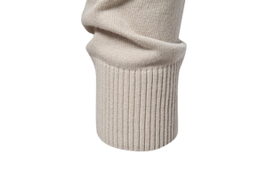 Close-up of beige knit sweater ribbed cuff showing fine texture and quality stitching