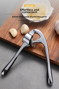 Close-up of manual garlic press with ergonomic handle on wooden board