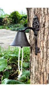 Close-up of vintage cast iron doorbell with key-shaped base on a tree trunk texture