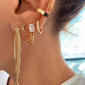 Close-up of gold tassel earrings and square zircon chain ear studs worn by a model
