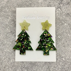 Sparkly green acrylic Christmas tree drop earrings with gold stars on a grey stone surface