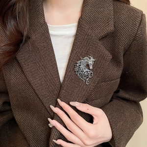 Detail of silver unicorn brooch with blue crystals on brown herringbone blazer