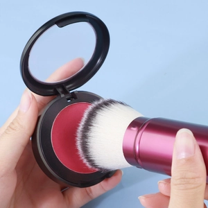 Close-up of a portable retractable purple makeup brush and a rose red powder compact