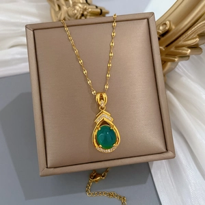Luxuriöse Goldkette mit tropfenförmigem grünem Stein und Diamanten auf weißer Seide