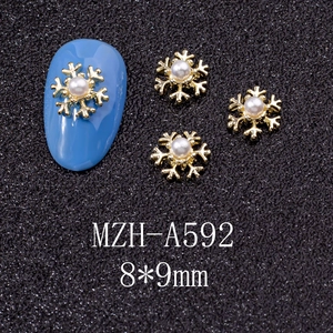 Macro shot of 8x9mm gold snowflake nail charms with pearl center on blue nail art