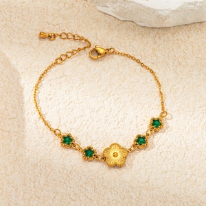 Macro detail of gold flower charm and green star gemstones on vintage titanium bracelet