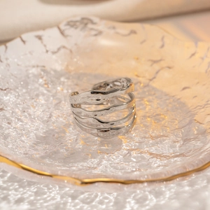 Detail of multi-layer silver textured open ring on a gold-rimmed glass plate