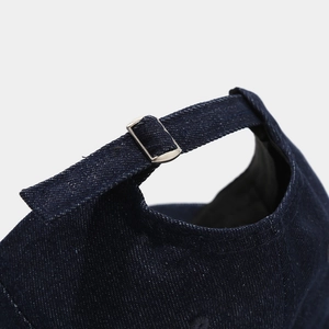 Detail of adjustable metal buckle on distressed denim baseball cap with fabric texture