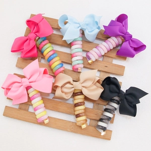 Set of six colorful bow phone cord hair ties displayed on a wooden stand