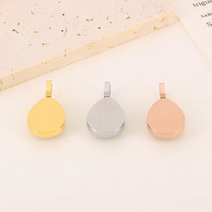 Three teardrop diamond pendants in gold, silver and rose gold on a natural stone base