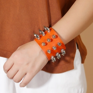 Close-up of orange leather punk bracelet with silver pyramid studs on model's wrist
